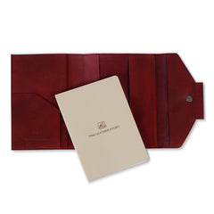 A red leather notebook organiser with a pen slider, closed with a regular book binding. The notebook appears to have a solid, smooth finish.