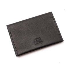 A closed black bi-fold credit card holder with visible stitching and a embossed logo on the front of the leather story