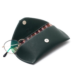 A green leather sunglass case with a magnetic button closure and a cotton-lined interior having glases.